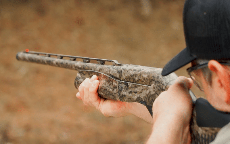 man aiming a cammo shotgun 