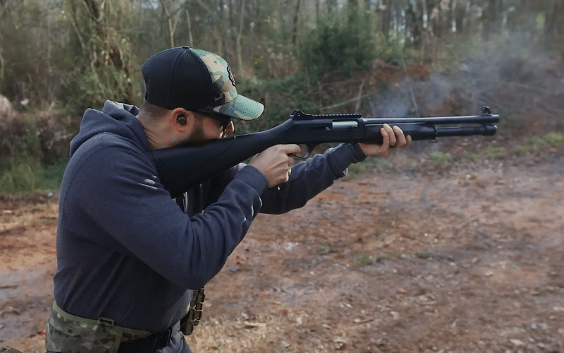 man shooting a shotgun with a pistol grip handle 