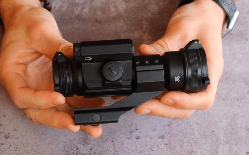 Hands holding a Vortex red dot sight
