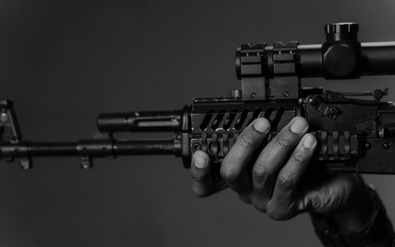 Black and white image of a hand holding a gun with quality optic