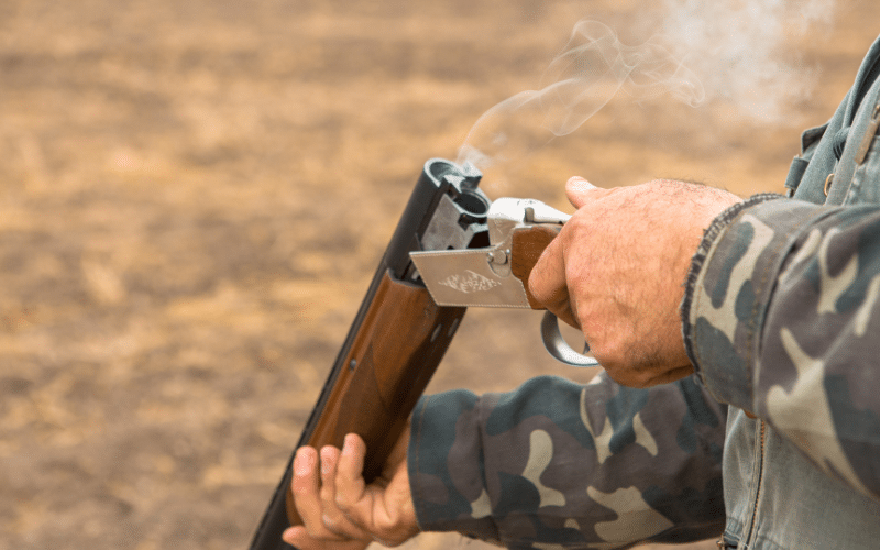 Man holding a shotgun with a smoking open chamber