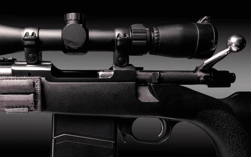 Rifle scope on a hunting rifle with a grey background 
