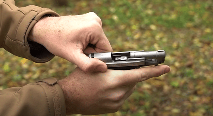 Hand holding the stainless steel frame of the Beretta Tomcat
