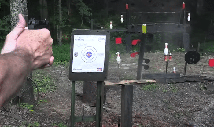 A person firing a true pocket pistol at targets in a forest

