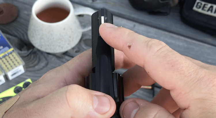 Finger pointing at the white tick on the front sight
