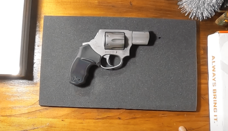 Silver and black Taurus pistol laid on a grey surface
