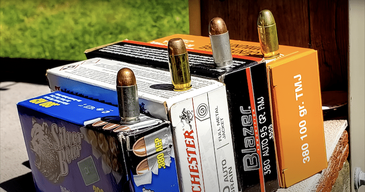 Different brands of 380 ammunition on top of each box with a grassy background