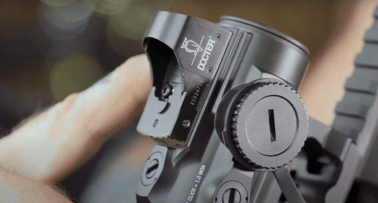 Finger pointing at a reflex sight on a prism scope