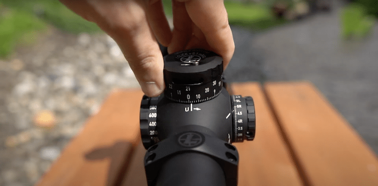 Fingers adjusting the elevation knob of a Mark 5HD scope