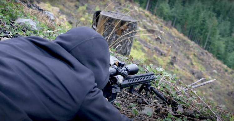 A person aiming a rifle at a target
