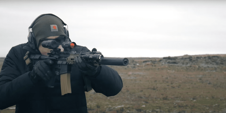 Man holding a rifle with a red dot sight
