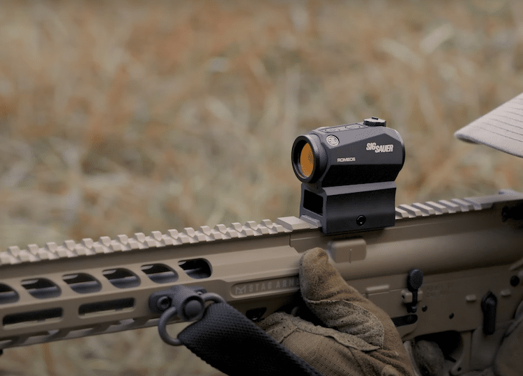 Romeo 5 on top of a rifle and a grassy background