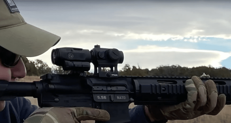 Man holding a rifle with red sight