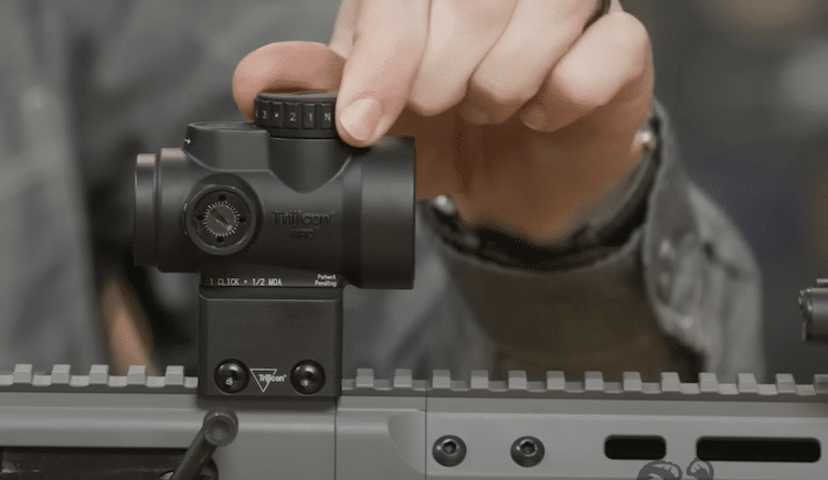 Fingers adjusting the knob of a Trijicon MRO