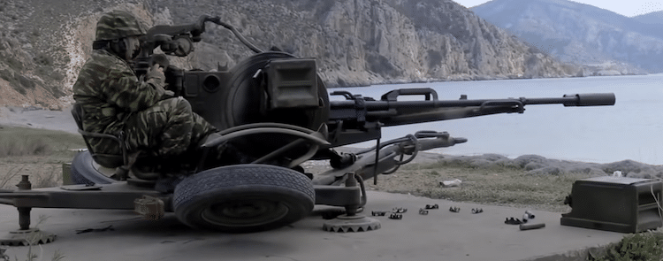 Soldier aiming the ZU-23-2 and a mountain and ocean in the background