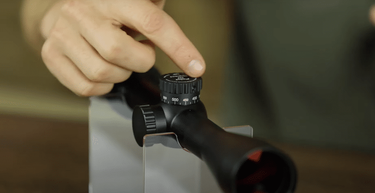 Finger pointing at the elevation knob of a Burris scope