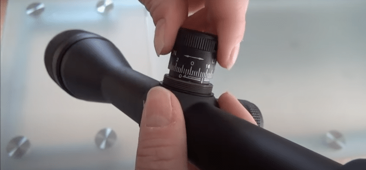 Fingers turning the elevation knob on a scope