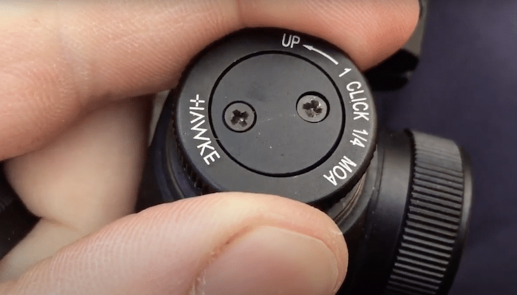Fingers adjusting the elevation knob of a Hawke scope