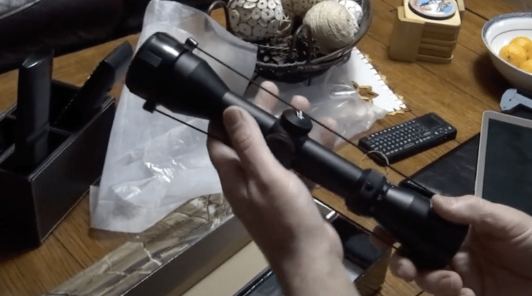 Excalibur Twilight DLX scope with lens cover held in both hands